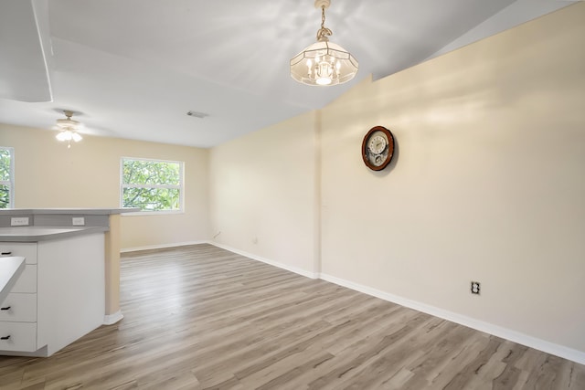 3048 SE Wake Rd, Port Saint Lucie, FL 34984 - unfurnished living room featuring light wood finished floors, a ceiling fan, baseboards, lofted ceiling, and a chandelier