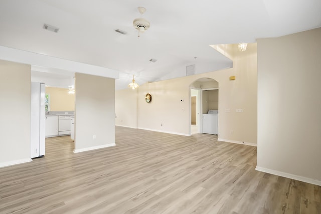 3048 SE Wake Rd, Port Saint Lucie, FL 34984 - unfurnished living room with washer / clothes dryer, light wood-style floors, vaulted ceiling, baseboards, and arched walkways
