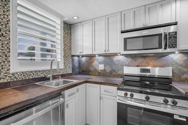 104 Paradise Harbour Blvd Unit 104, North Palm Beach, FL 33408 - kitchen with stainless steel appliances, a sink, dark countertops, decorative backsplash, and a textured ceiling