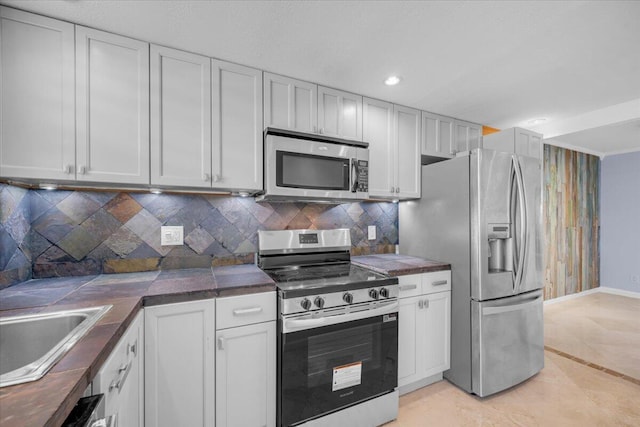 104 Paradise Harbour Blvd Unit 104, North Palm Beach, FL 33408 - kitchen featuring appliances with stainless steel finishes, dark countertops, decorative backsplash, baseboards, and white cabinetry