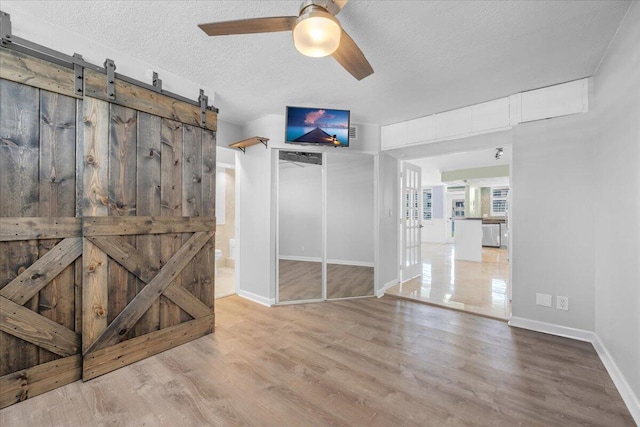 104 Paradise Harbour Blvd Unit 104, North Palm Beach, FL 33408 - unfurnished bedroom featuring wood finished floors, baseboards, a textured ceiling, and a barn door