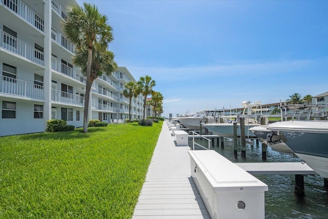 104 Paradise Harbour Blvd Unit 104, North Palm Beach, FL 33408 - dock area featuring boat lift, a water view, and a lawn