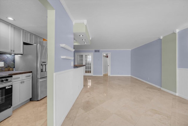 104 Paradise Harbour Blvd Unit 104, North Palm Beach, FL 33408 - kitchen featuring appliances with stainless steel finishes, ornamental molding, a wainscoted wall, backsplash, and gray cabinets