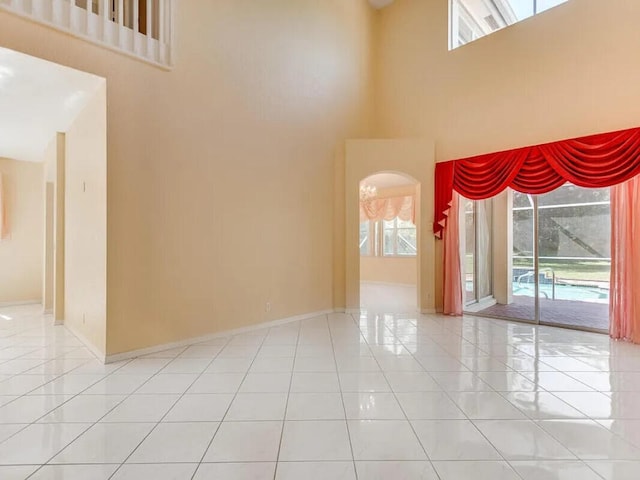 11353 Sea Grass Cir, Boca Raton, FL 33498 - tiled spare room featuring arched walkways, a high ceiling, and baseboards