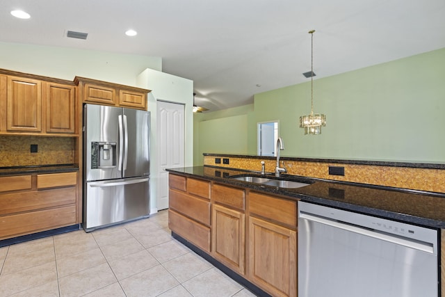 2683 SW Marquis Ter, Stuart, FL 34997 - kitchen with appliances with stainless steel finishes, decorative backsplash, brown cabinetry, a chandelier, and pendant lighting