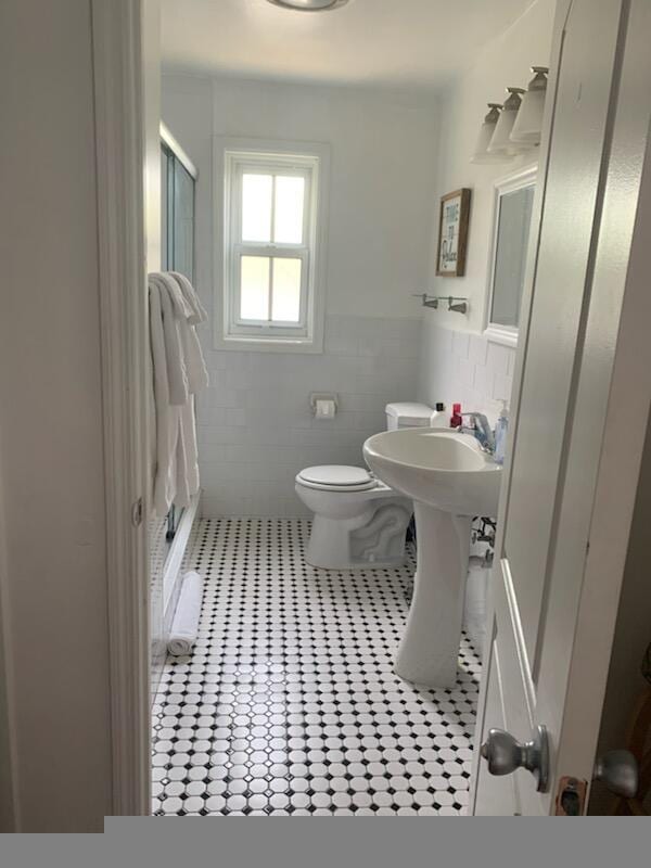 723 N Federal Hwy, Lake Worth Beach, FL 33460 - full bathroom featuring a stall shower, tile patterned floors, toilet, tile walls, and a wainscoted wall