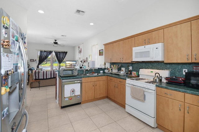 107 NW Summerville Ct, Port Saint Lucie, FL 34986 - kitchen featuring appliances with stainless steel finishes, dark countertops, a peninsula, backsplash, and a ceiling fan
