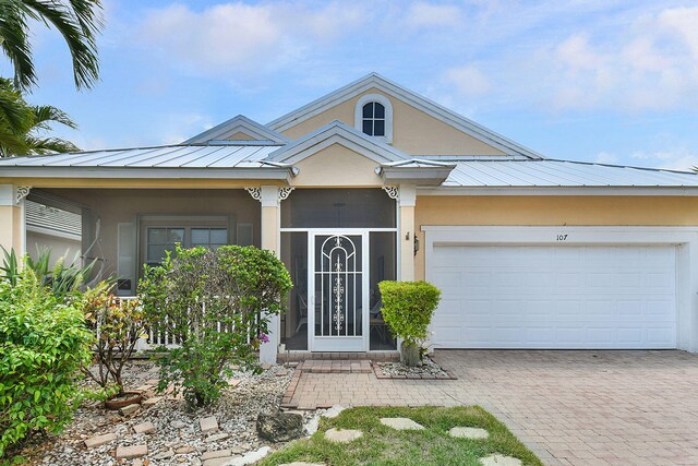 107 NW Summerville Ct, Port Saint Lucie, FL 34986 - view of front of property with decorative driveway, stucco siding, a metal roof, a garage, and a standing seam roof