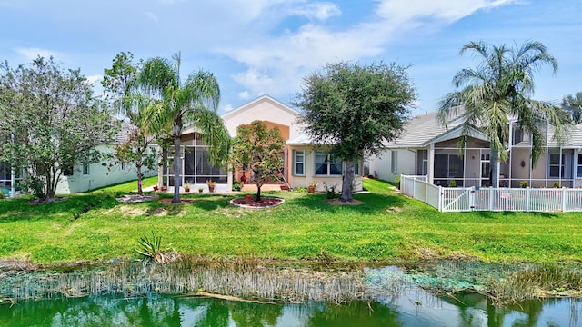 107 NW Summerville Ct, Port Saint Lucie, FL 34986 - rear view of house featuring a sunroom, a yard, stucco siding, and a water view
