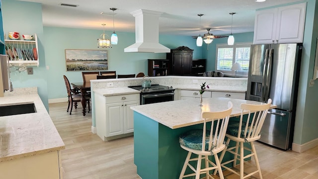 4575 SW Bimini Cir S, Palm City, FL 34990 - kitchen featuring appliances with stainless steel finishes, island exhaust hood, a center island, light wood-style flooring, and a ceiling fan