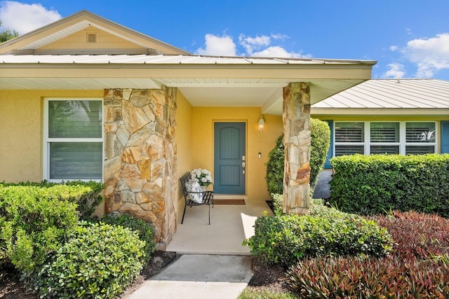 4575 SW Bimini Cir S, Palm City, FL 34990 - view of exterior entry featuring stone siding, stucco siding, a metal roof, and a standing seam roof