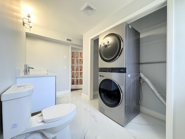307 4th St, Lake Park, FL 33403 - bathroom featuring stacked washing machine and dryer, marble look tile flooring, a sink, and baseboards