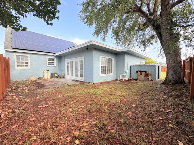 307 4th St, Lake Park, FL 33403 - back of property with french doors, stucco siding, roof mounted solar panels, and central AC