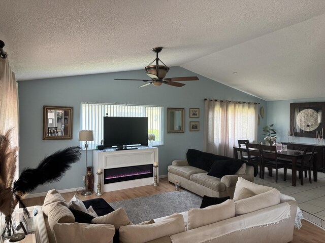 8700 NW 46th Ct, Lauderhill, FL 33351 - living area featuring vaulted ceiling, a ceiling fan, wood finished floors, a warm lit fireplace, and a textured ceiling