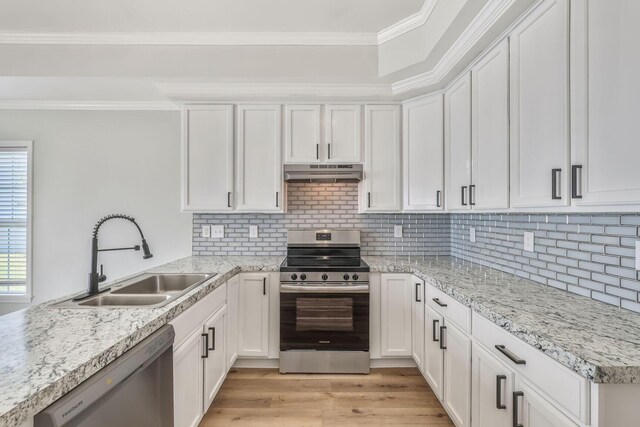 3322 Monterey Square Ln Unit 104, Fort Pierce, FL 34982 - kitchen with appliances with stainless steel finishes, under cabinet range hood, a sink, white cabinetry, and crown molding