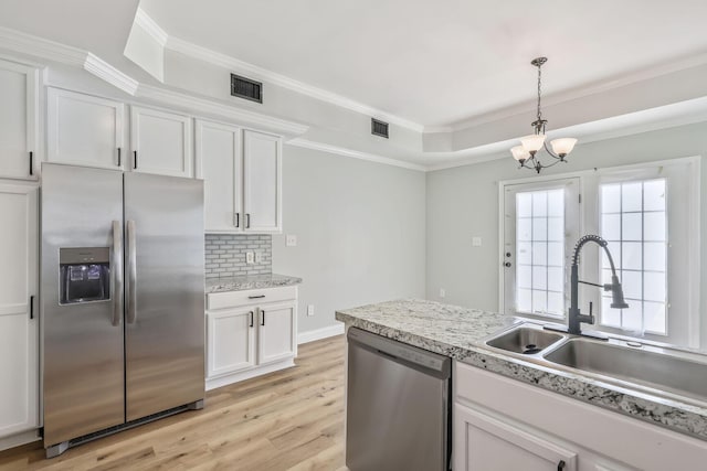 3322 Monterey Square Ln Unit 104, Fort Pierce, FL 34982 - kitchen with appliances with stainless steel finishes, a sink, light wood-type flooring, decorative backsplash, and white cabinetry
