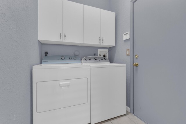 10664 Royal Caribbean Cir, Boynton Beach, FL 33437 - laundry room with cabinet space, washer and clothes dryer, a textured wall, and light tile patterned flooring