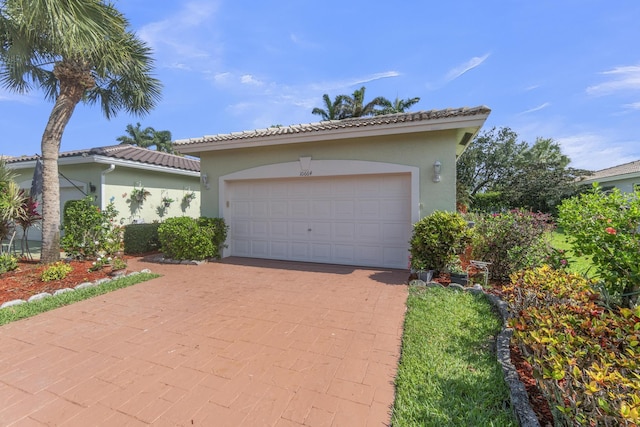 10664 Royal Caribbean Cir, Boynton Beach, FL 33437 - mediterranean / spanish-style house featuring stucco siding, decorative driveway, an attached garage, and a tiled roof