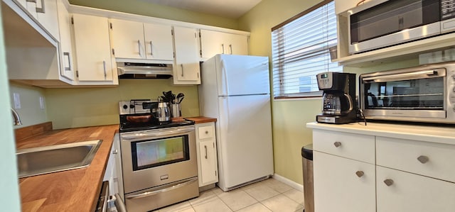 4299 NW 16th St Unit 303, Lauderhill, FL 33313 - kitchen with under cabinet range hood, stainless steel appliances, white cabinetry, butcher block counters, and light tile patterned floors