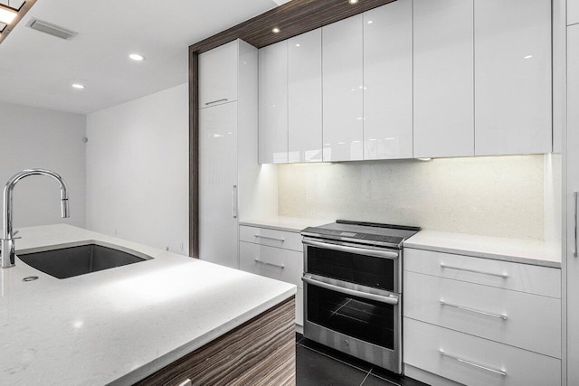 5779 Regency Cir W, Boca Raton, FL 33496 - kitchen featuring range with two ovens, modern cabinets, a sink, white cabinetry, and backsplash