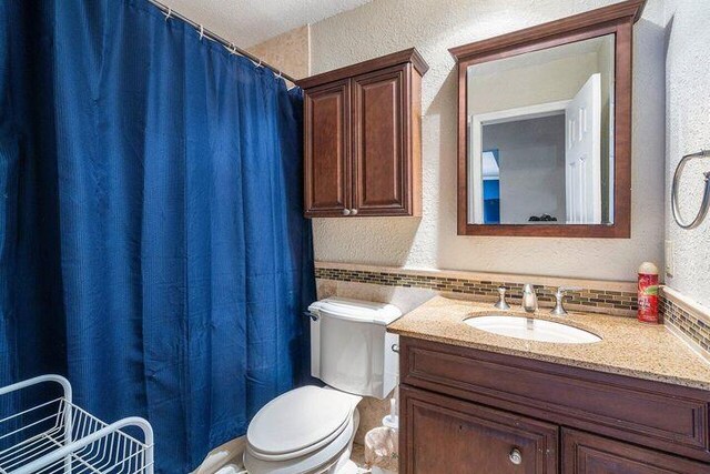 803 Mallard Dr, Delray Beach, FL 33444 - full bathroom featuring a textured wall, toilet, vanity, a shower with curtain, and tasteful backsplash