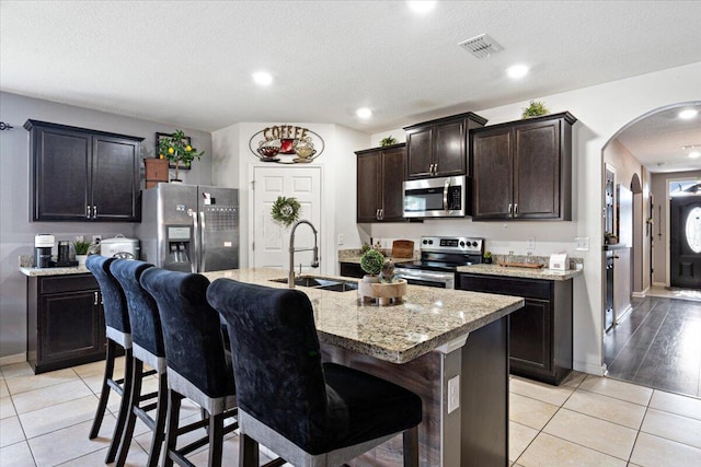 3313 SW Ludlow St, Port Saint Lucie, FL 34953 - kitchen featuring stainless steel appliances, a sink, arched walkways, light tile patterned floors, and a breakfast bar