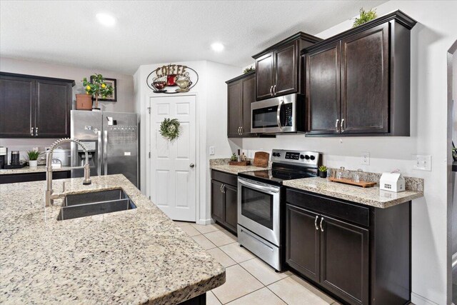 3313 SW Ludlow St, Port Saint Lucie, FL 34953 - kitchen with appliances with stainless steel finishes, light tile patterned flooring, a sink, dark brown cabinets, and light stone countertops