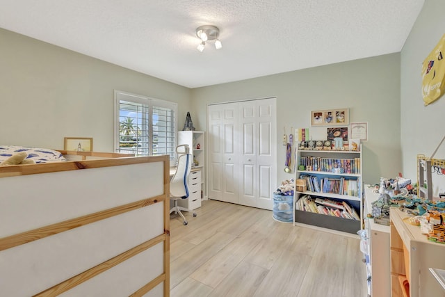 2703 SW Glenmoor Way, Palm City, FL 34990 - bedroom featuring light wood-style flooring, a closet, a textured ceiling, and a desk