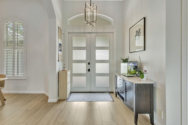 2703 SW Glenmoor Way, Palm City, FL 34990 - entrance foyer with light wood-style floors, a chandelier, arched walkways, french doors, and baseboards
