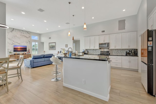 2703 SW Glenmoor Way, Palm City, FL 34990 - kitchen featuring appliances with stainless steel finishes, a towering ceiling, dark countertops, open floor plan, and white cabinets