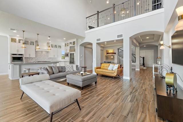 515 Sonoma Isles Cir, Jupiter, FL 33478 - living room with arched walkways, light wood finished floors, baseboards, stairs, and a towering ceiling