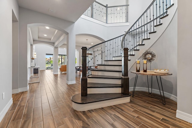 515 Sonoma Isles Cir, Jupiter, FL 33478 - stairway featuring arched walkways, wood tiled floors, baseboards, a high ceiling, and recessed lighting