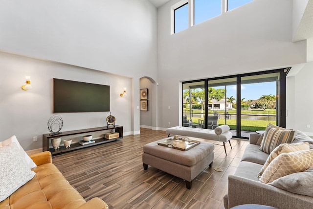 515 Sonoma Isles Cir, Jupiter, FL 33478 - living room featuring arched walkways, wood finished floors, a towering ceiling, and baseboards