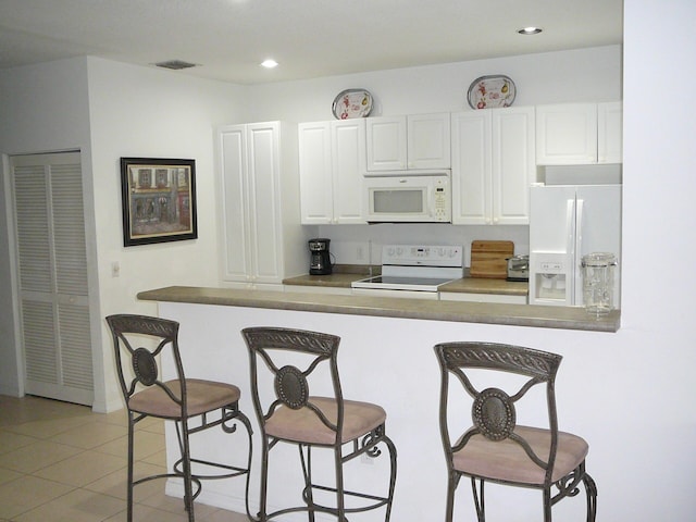 1840 E Sanderling Ln Unit 1, Fort Pierce, FL 34982 - kitchen with white appliances, a breakfast bar, white cabinetry, recessed lighting, and light tile patterned flooring