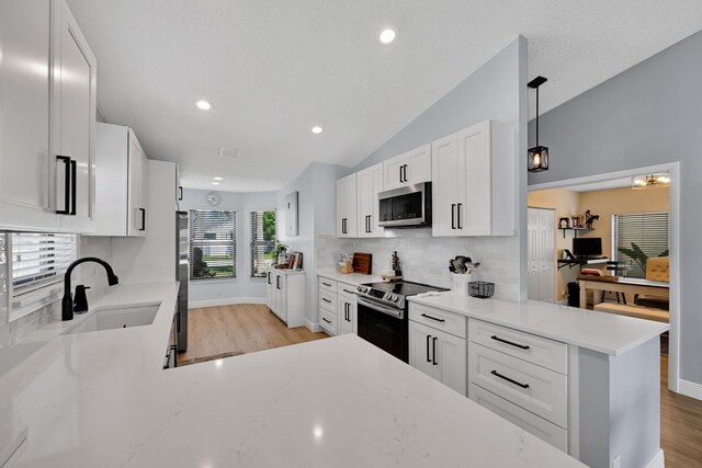 23283 Boca Trace Dr, Boca Raton, FL 33433 - kitchen featuring appliances with stainless steel finishes, light wood-style floors, lofted ceiling, tasteful backsplash, and recessed lighting