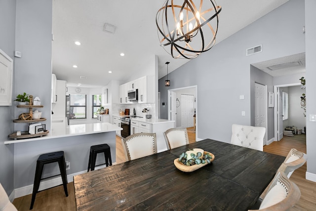 23283 Boca Trace Dr, Boca Raton, FL 33433 - dining area featuring light wood-style floors, high vaulted ceiling, baseboards, recessed lighting, and a chandelier
