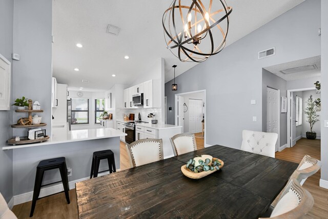 23283 Boca Trace Dr, Boca Raton, FL 33433 - dining area featuring light wood finished floors, recessed lighting, baseboards, high vaulted ceiling, and a chandelier
