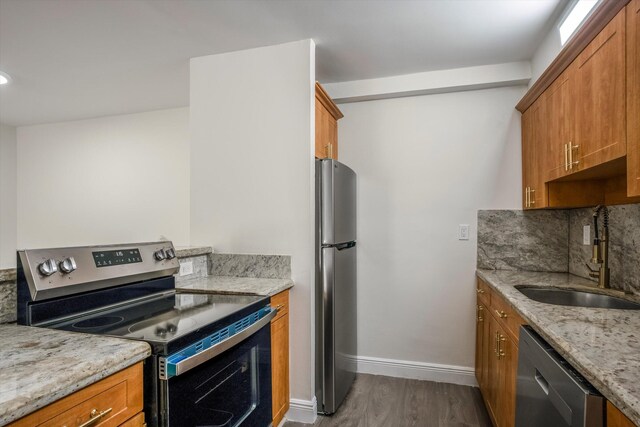 1673 Bay Rd Unit 206, Miami Beach, FL 33139 - kitchen featuring appliances with stainless steel finishes, a sink, brown cabinets, wood finished floors, and decorative backsplash