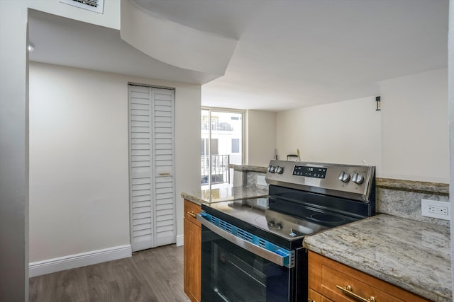 1673 Bay Rd Unit 206, Miami Beach, FL 33139 - kitchen with stainless steel electric range, brown cabinets, wood finished floors, baseboards, and light stone countertops
