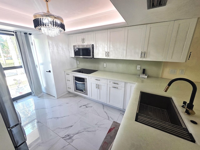 1731 Presidential Way Unit C201, West Palm Beach, FL 33401 - kitchen with appliances with stainless steel finishes, a tray ceiling, a chandelier, and white cabinets
