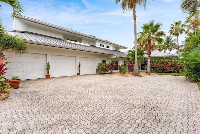 2150 SE Golfview Ln, Stuart, FL 34996 - view of front facade with a standing seam roof, metal roof, decorative driveway, and stucco siding