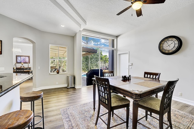 17233 Bermuda Village Dr, Boca Raton, FL 33487 - dining space with a textured ceiling, a ceiling fan, arched walkways, light wood-style flooring, and baseboards