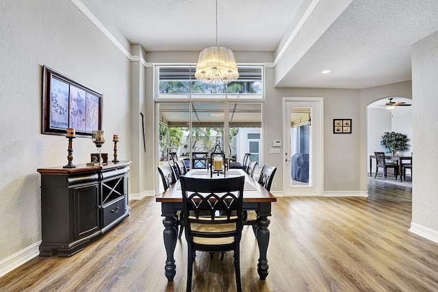 17233 Bermuda Village Dr, Boca Raton, FL 33487 - dining space featuring light wood-type flooring, a chandelier, baseboards, a textured ceiling, and arched walkways