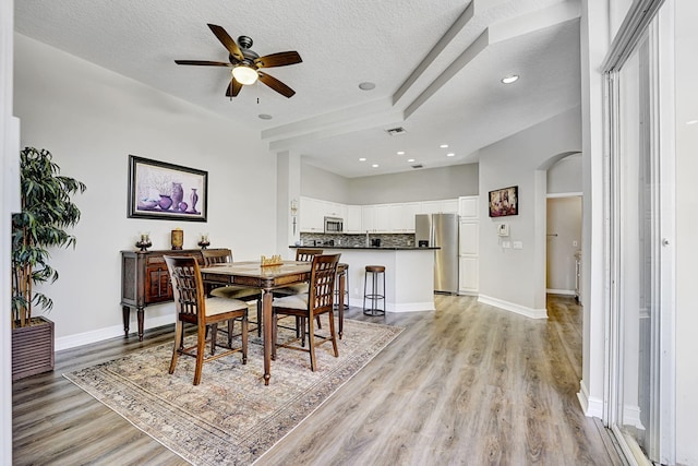 17233 Bermuda Village Dr, Boca Raton, FL 33487 - dining room with a ceiling fan, light wood-type flooring, arched walkways, a textured ceiling, and baseboards