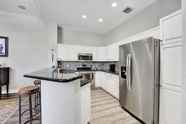 17233 Bermuda Village Dr, Boca Raton, FL 33487 - kitchen featuring appliances with stainless steel finishes, a kitchen bar, light wood-style floors, white cabinets, and recessed lighting