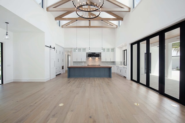 18072 127th Dr N, Jupiter, FL 33478 - kitchen with wood counters, high vaulted ceiling, a barn door, white cabinetry, and decorative backsplash