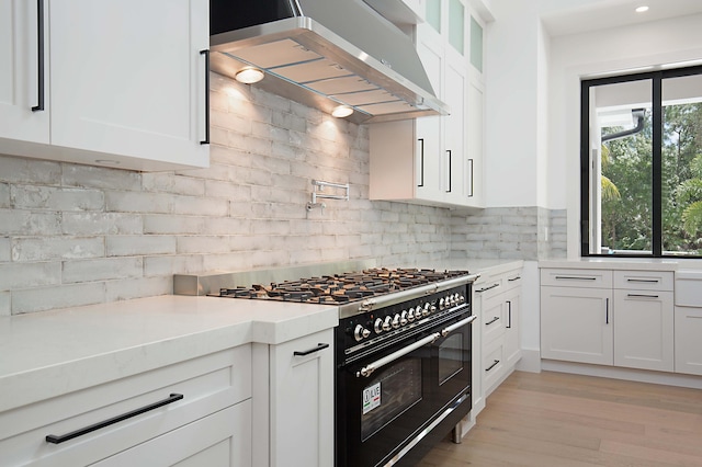 18072 127th Dr N, Jupiter, FL 33478 - kitchen featuring double oven range, wall chimney range hood, white cabinets, light countertops, and decorative backsplash