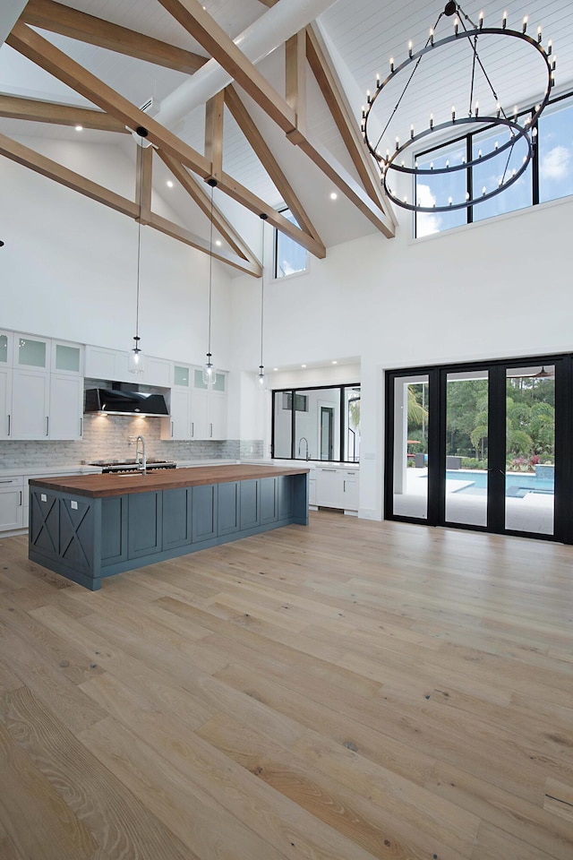 18072 127th Dr N, Jupiter, FL 33478 - kitchen featuring high vaulted ceiling, exhaust hood, open floor plan, white cabinetry, and beamed ceiling