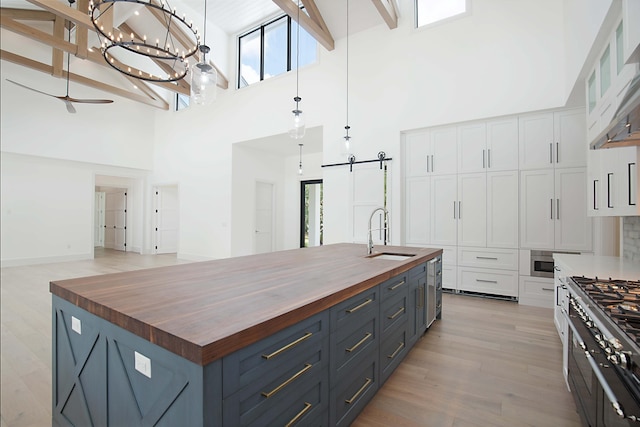 18072 127th Dr N, Jupiter, FL 33478 - kitchen with wood counters, a sink, a high ceiling, a barn door, and white cabinets