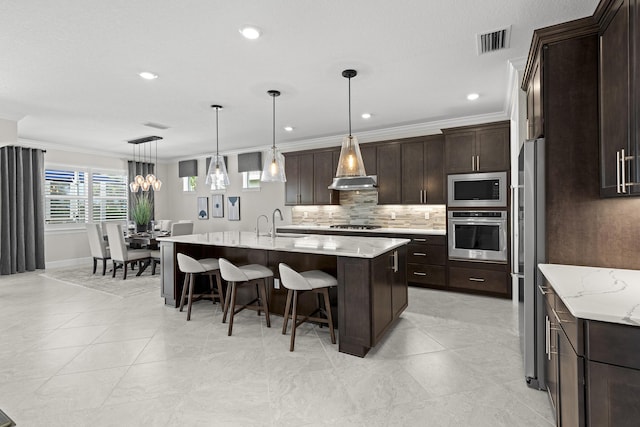 10339 SW Tetian Dr, Port Saint Lucie, FL 34987 - kitchen with appliances with stainless steel finishes, tasteful backsplash, a kitchen bar, a kitchen island with sink, and dark brown cabinetry
